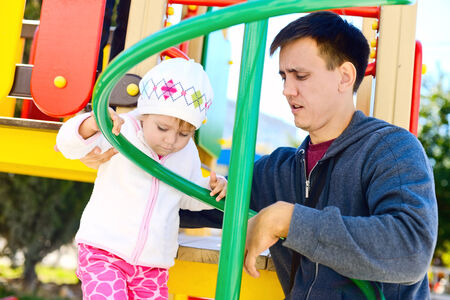 father helping  daughter to climb on the playgroundの写真素材