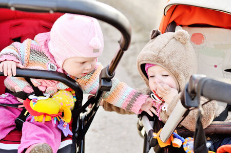stroller friends sitting and playing, one girl wanting to take dummy away from another baby girlの写真素材