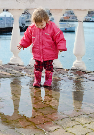 happy childhood of baby girl walking in puddleの写真素材