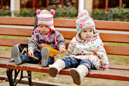 baby friends sitting on the benchの写真素材