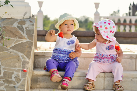 two baby friends sitting on the stairsの写真素材