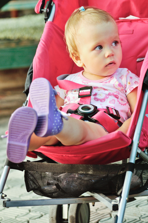 baby girl sitting in red strollerの写真素材
