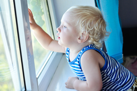 baby boy looking through the windowの写真素材