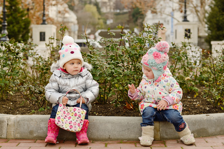 funny toddler friends are sitting on the borderの写真素材