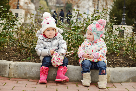 funny toddler friends are sitting on the borderの写真素材