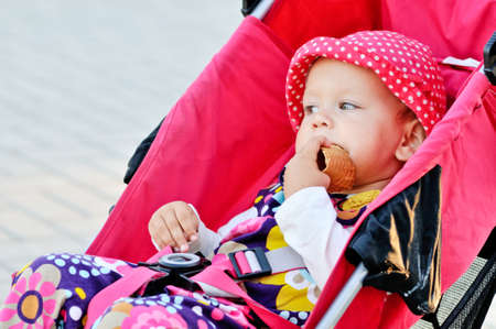 baby sitting in stroller and eating  waferの写真素材