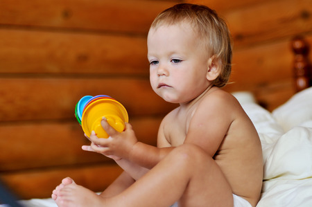 toddler with toy sitting on the bedの写真素材