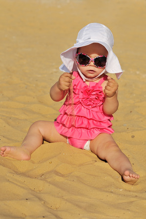 cute summer baby sitting on the beachの写真素材
