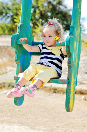 swinging toddler girl with flowers in handの写真素材