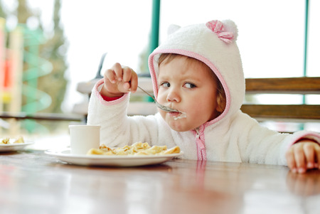 toddler girl eating in outdoor cafeの写真素材