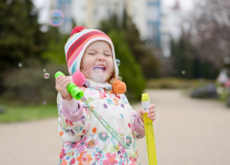 happy playful toddler girl with soap bubblesの写真素材