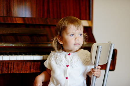 baby girl sitting next to the pianoの写真素材