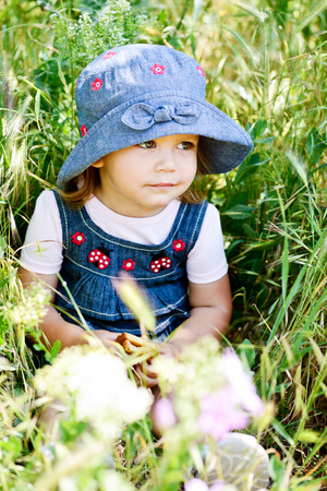 toddler girl sitting in the green grassの写真素材
