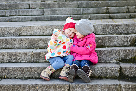 two toddler friends sitting on the stairsの写真素材