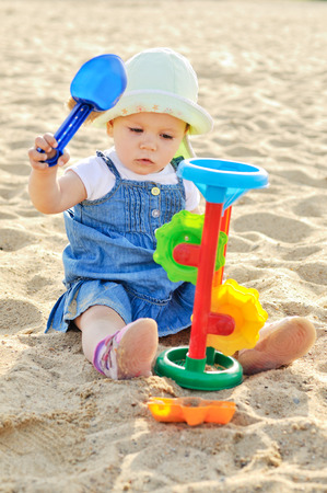 cute baby girl playing on the beach with sandの写真素材