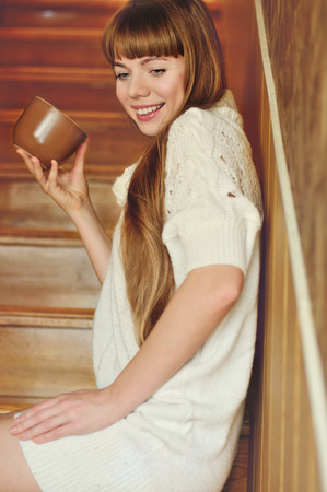 girl with mug of hot drink on the stairsの写真素材