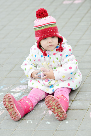 toddler girl with chalk sitting outdoorsの写真素材