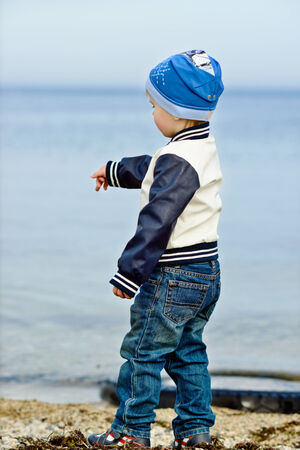 toddler boy dropping stones in the seaの写真素材