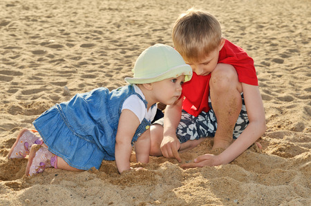brother and sister  in the sand at the beachの写真素材