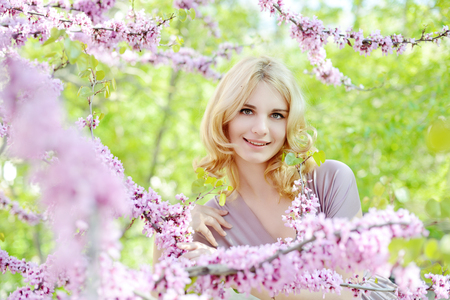 Happy young woman in spring flowers gardenの写真素材