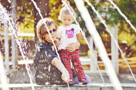 Woman with child playing against splashes of waterの写真素材