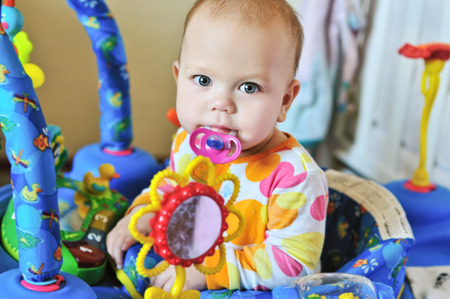 funny baby with dummy in baby jumper の写真素材