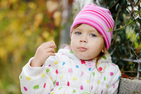 funny toddler girl eating outdoorsの写真素材