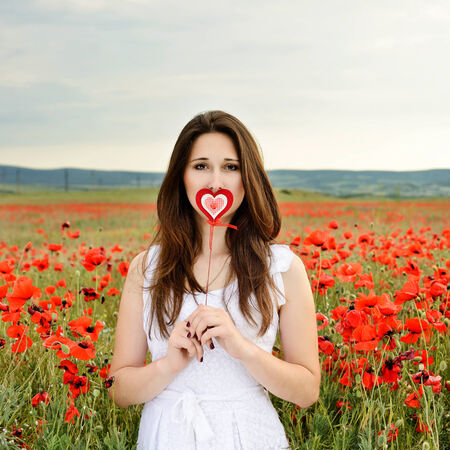 girl with heart in poppy fieldの写真素材