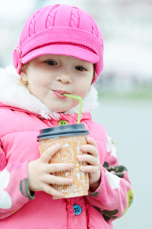 toddler girl with hot drink on the streetの写真素材