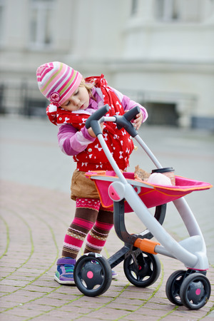 toddler girl with toy stroller outsideの写真素材