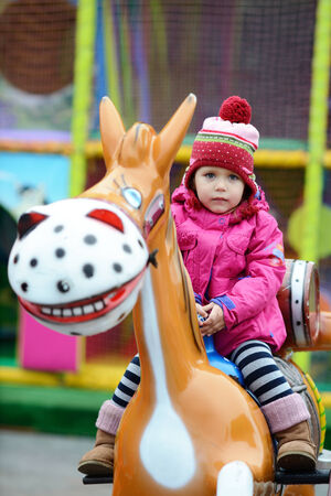 toddler girl  in theme park  on the horseの写真素材