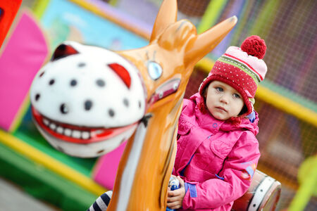 toddler girl  in theme park  on the horseの写真素材