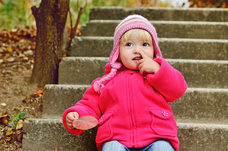 baby girl picking her nose outdoorsの写真素材