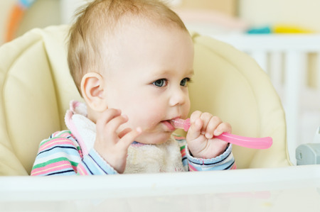 baby in chair  with spoonの写真素材