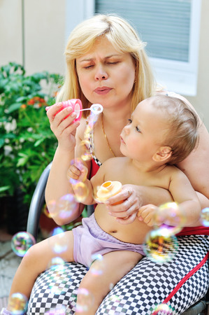 mature mother with baby blowing soap bubblesの写真素材