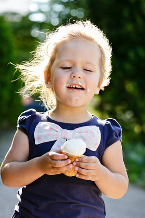 little girl eating an ice-cream in the summerの写真素材