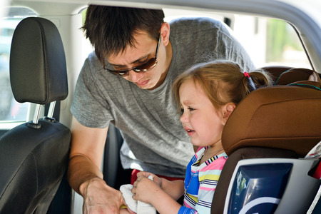 father  fastening  crying  daughter   in carの写真素材