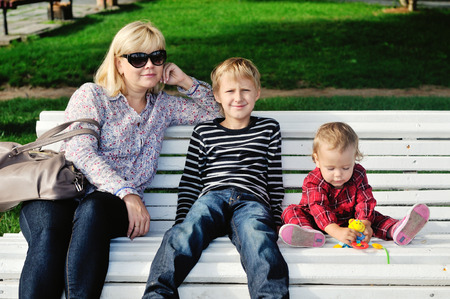 woman with two children sitting on the benchの写真素材