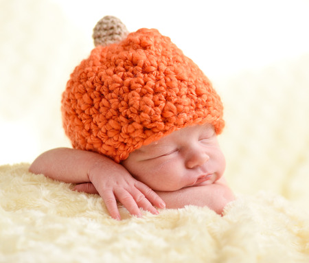 sweet newborn wearing orange hatの写真素材