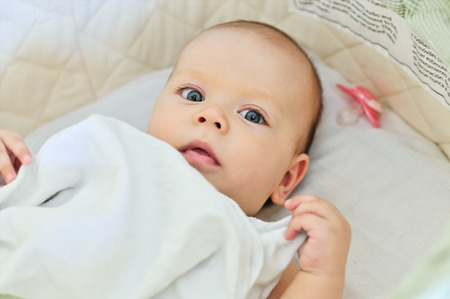 blue eyed baby laying in cribの写真素材