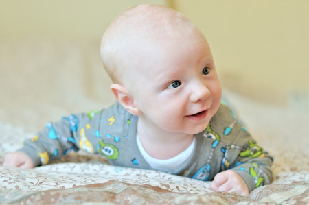 Baby boy lying on bedの写真素材