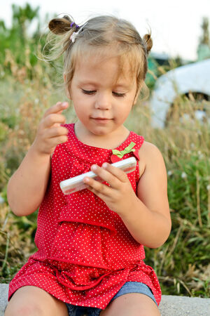 toddler girl playing  smartphone outdoorsの写真素材