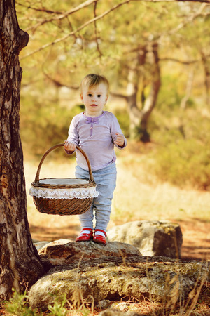 baby girl  with basket in fall parkの写真素材