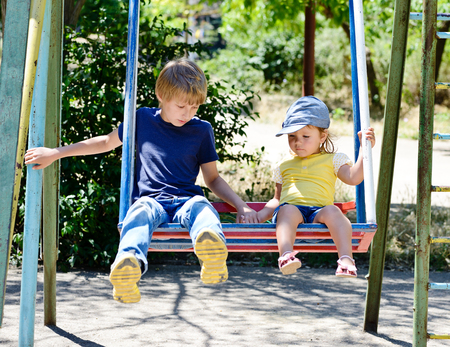 brother and sister on the swing in the parkの写真素材