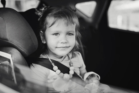child in car in seat with belt on shoulderの写真素材
