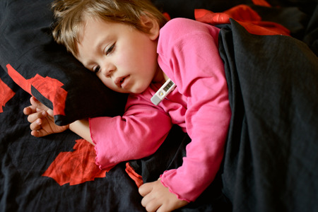 toddler girl  is ill and she is laying in the bedの写真素材