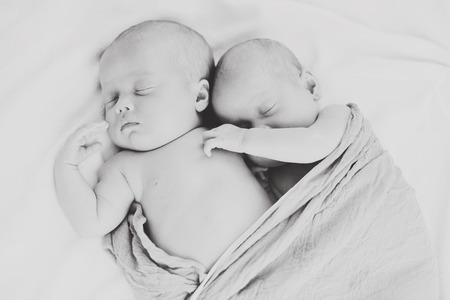 sweet twins are sleeping and hugging in soft focus
