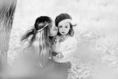 woman kissing her little daughter in fall timeの写真素材