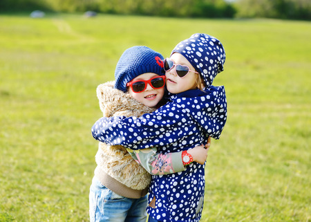 two little girls are hugging in spring fieldの写真素材