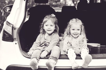 laughing toddler girls sitting in the carの写真素材